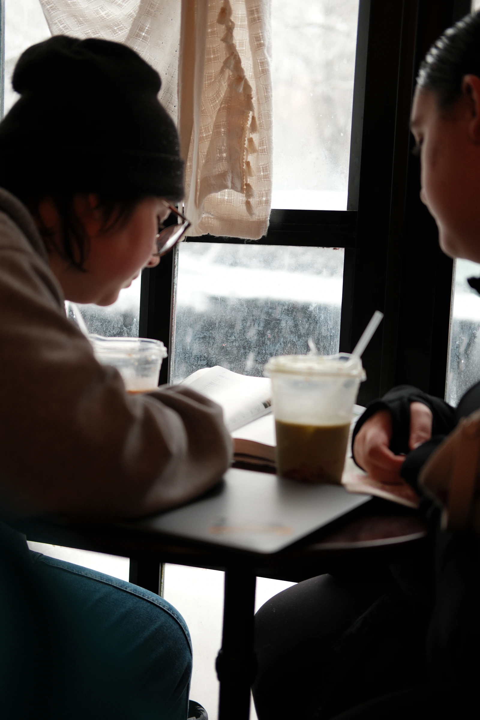 Two people reading and talking at a café table